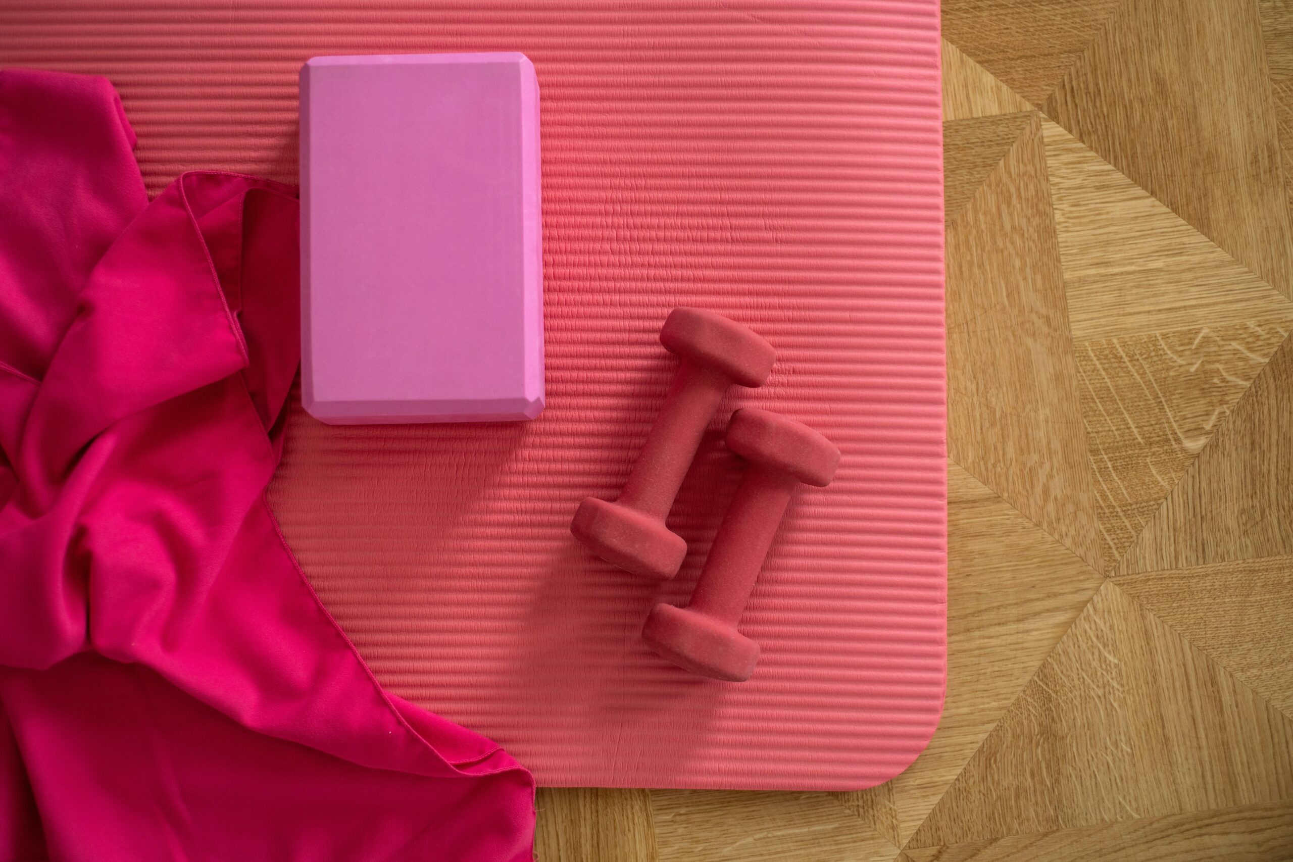 a pink yoga mat with dumbbells and a pink towel